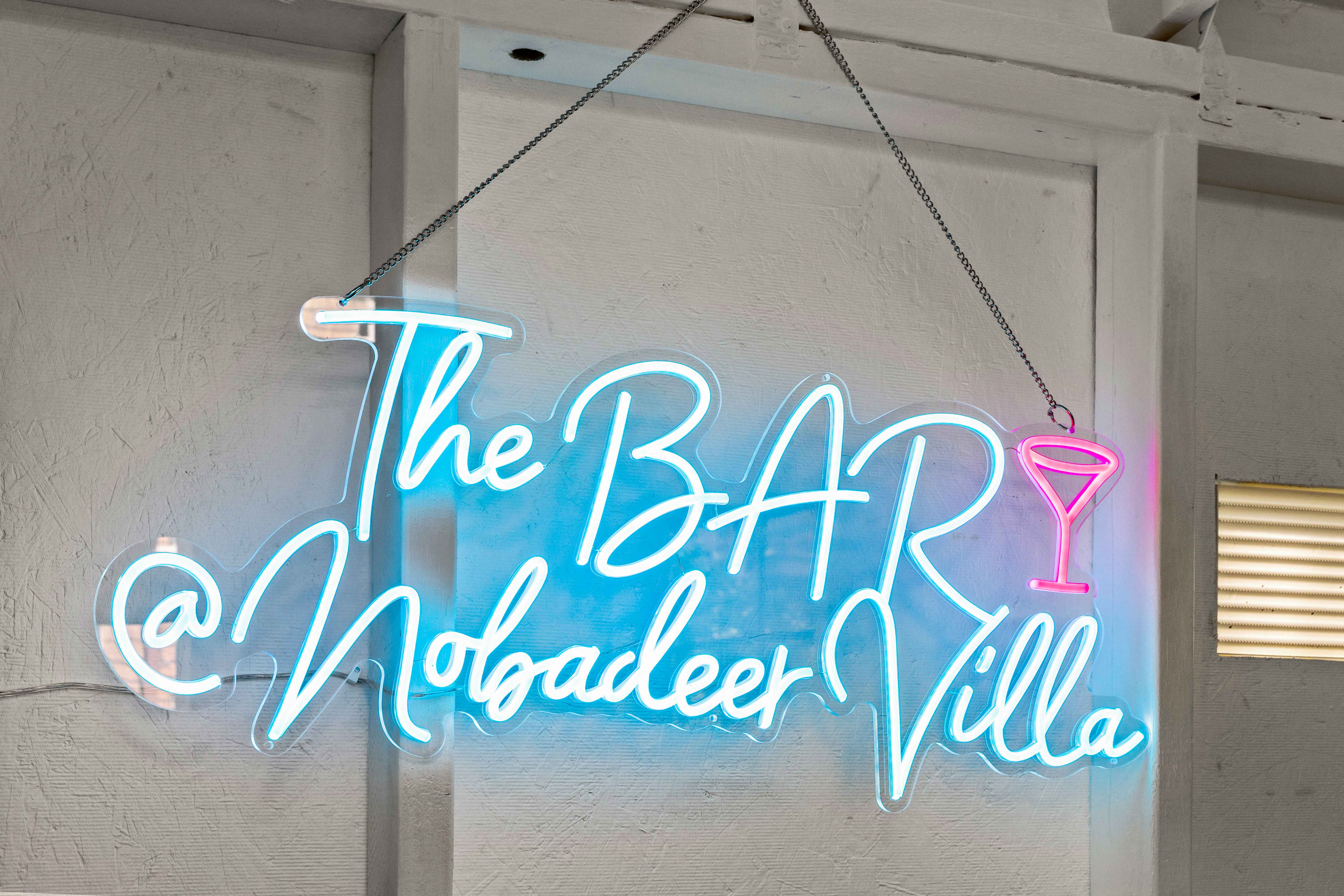 Close-up of the neon sign reading "The Bar @ Nobadeer Villa" with a pink martini glass