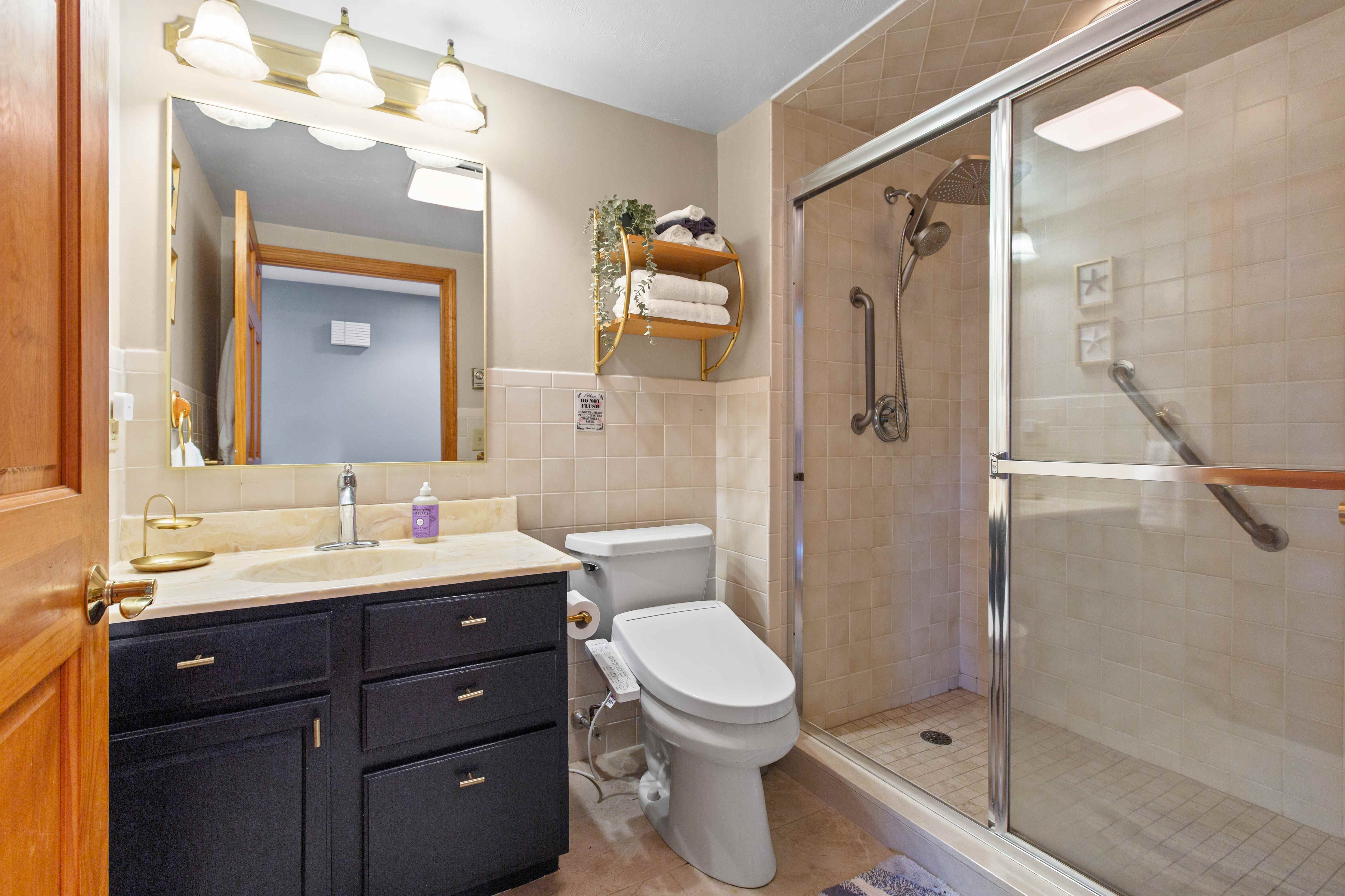 Bathroom with a navy vanity, brass fixtures, cream marble top, and a glass sliding-door tile shower
