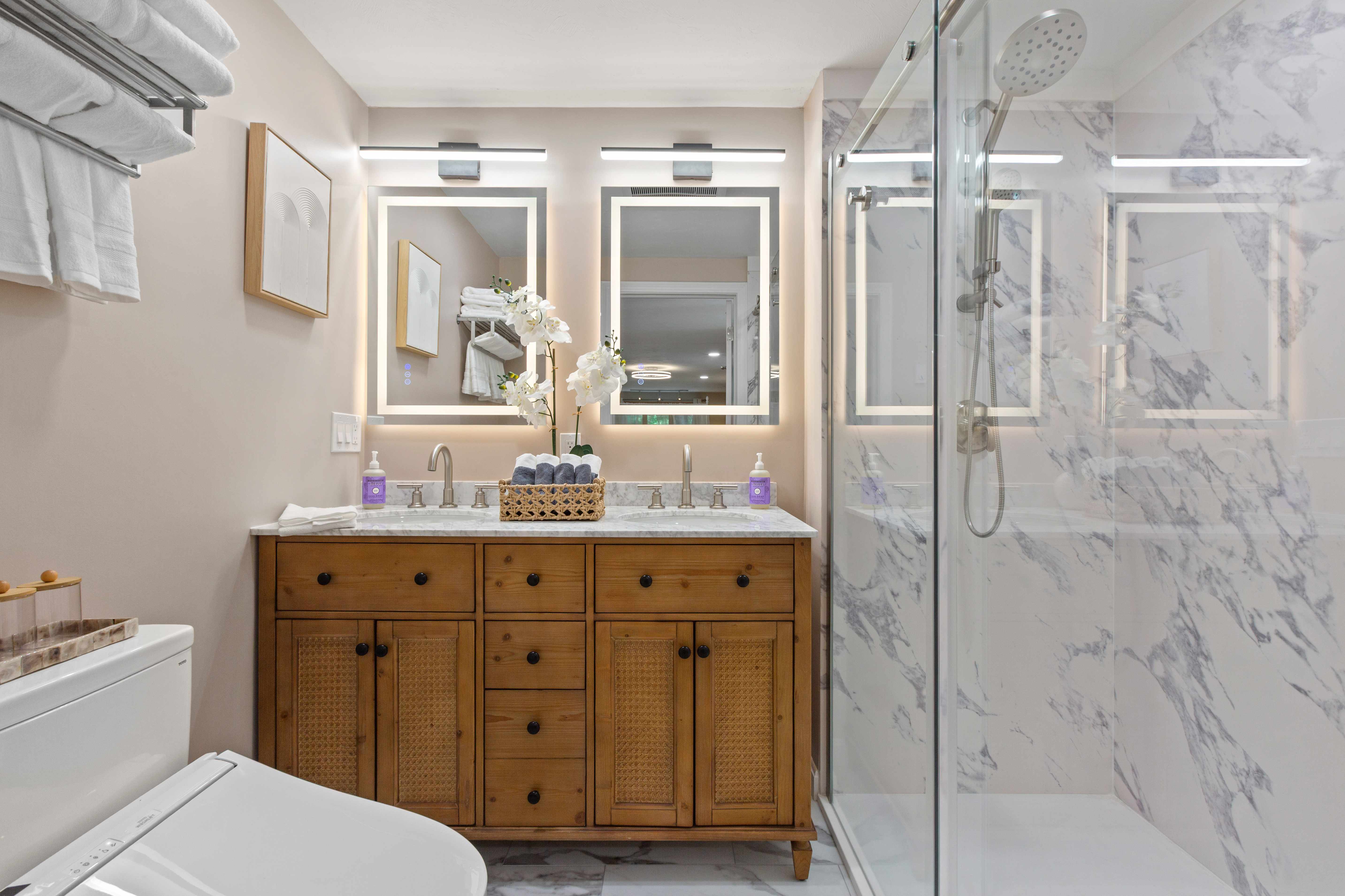 Lighthouse Suite en-suite with a double wood vanity, backlit LED mirrors, and a marble glass shower