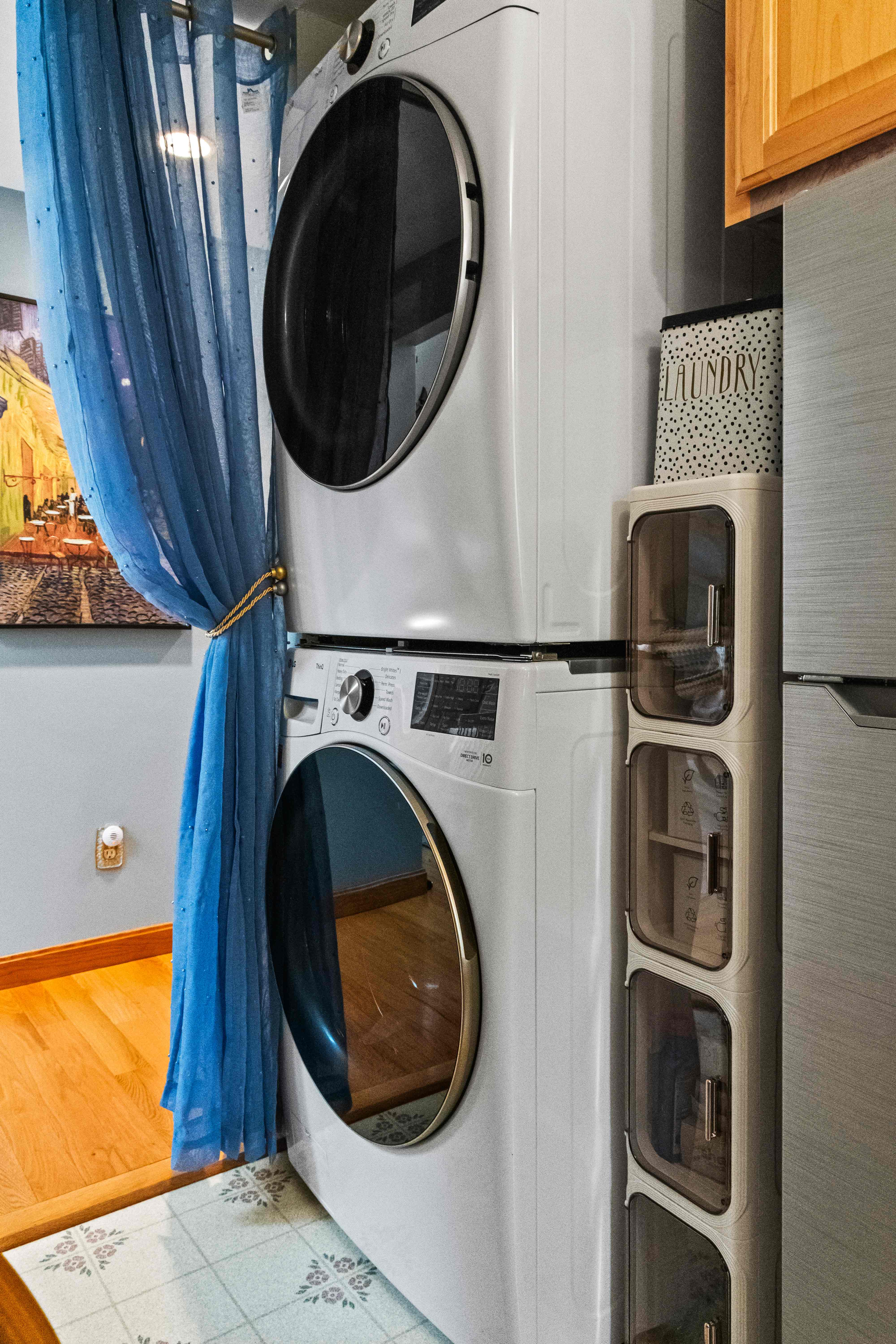 Stacked washer and dryer beside the Bistro Bar with a blue privacy curtain and laundry storage