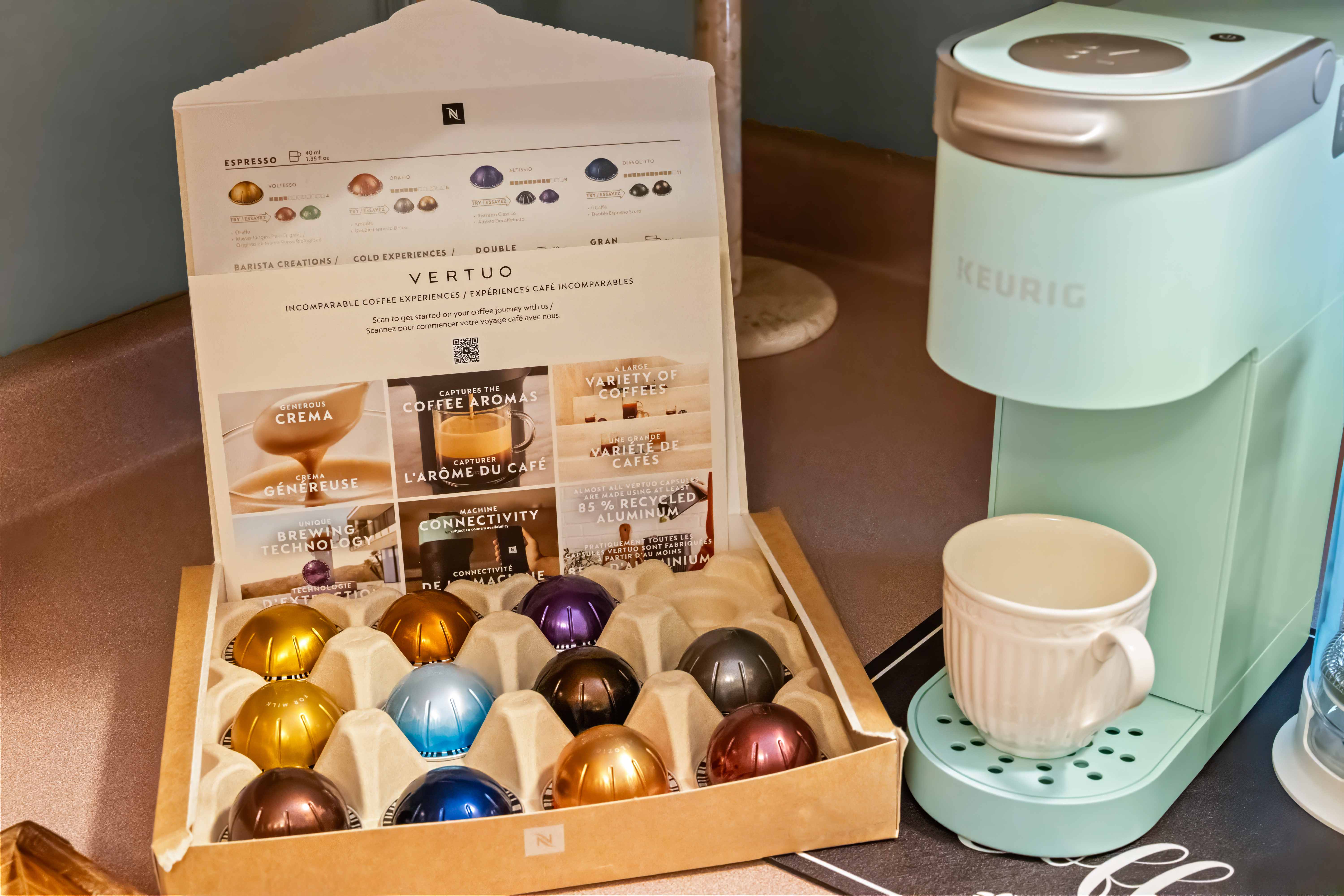 Nespresso coffee station with a mint-green machine, cups, and an assortment of colorful capsules