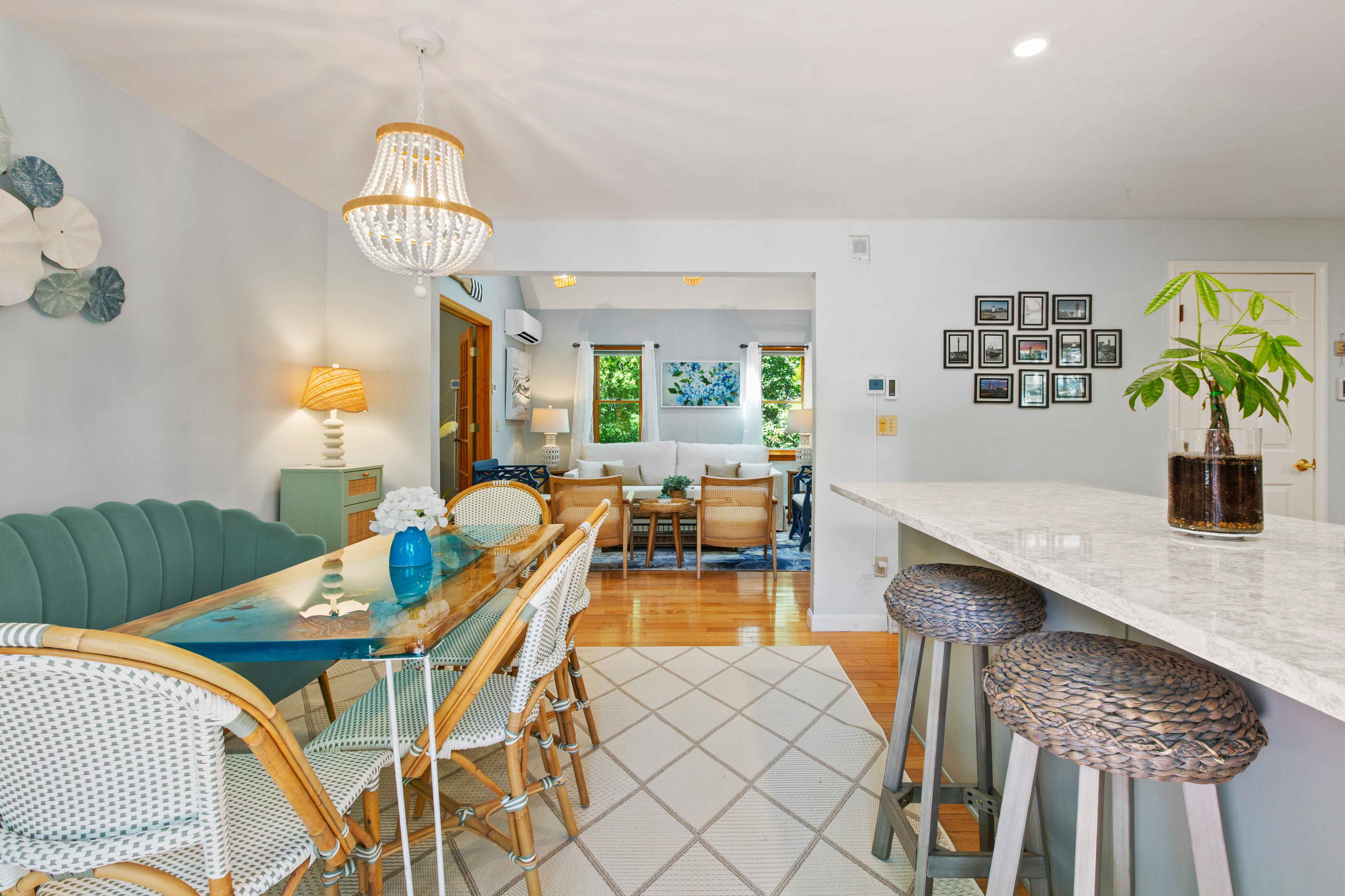 Wide view from the breakfast area into the open living room with the kitchen island and woven bar stools alongside