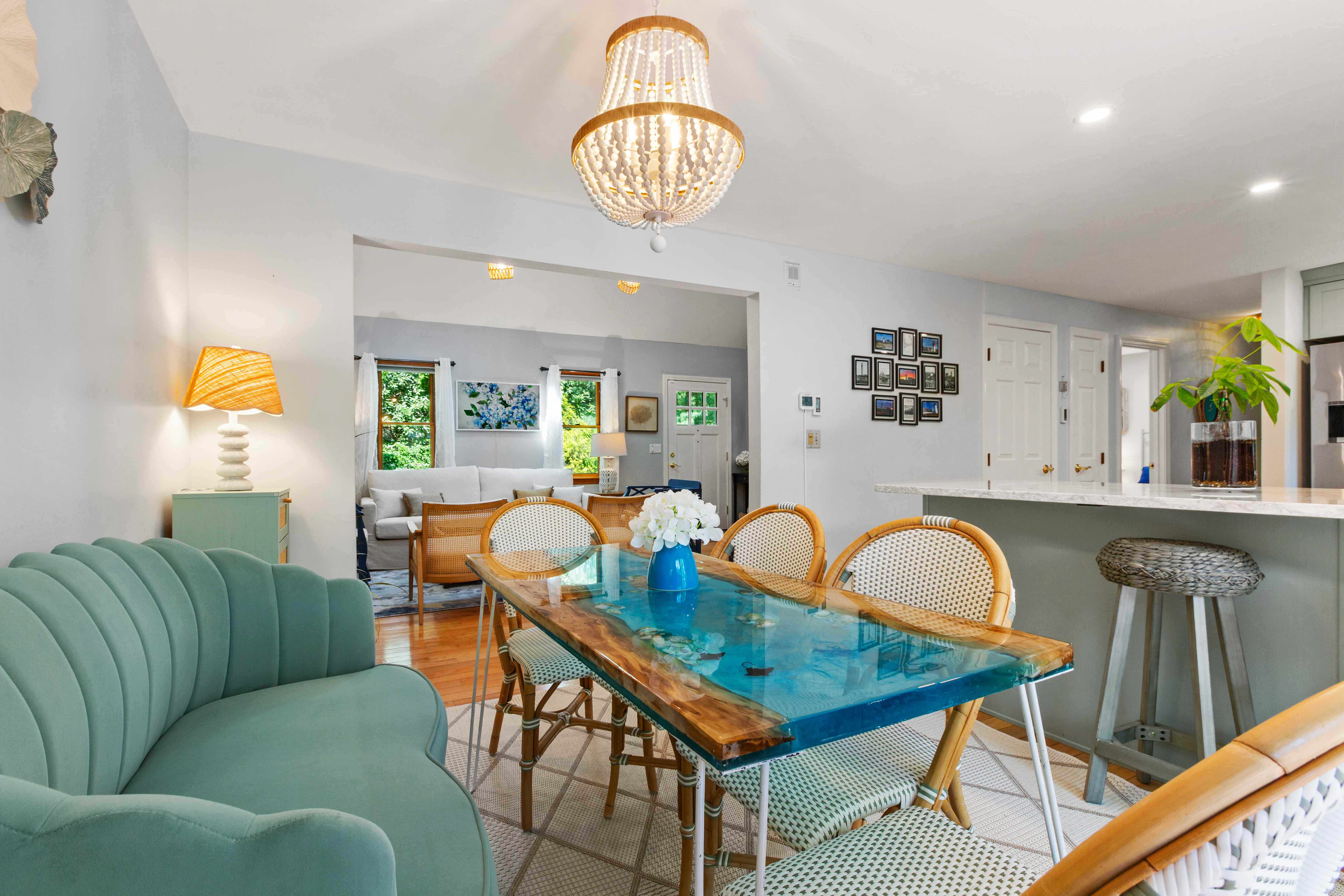Breakfast area and living room connection with a turquoise river table, scalloped banquette, and bright coastal furnishings