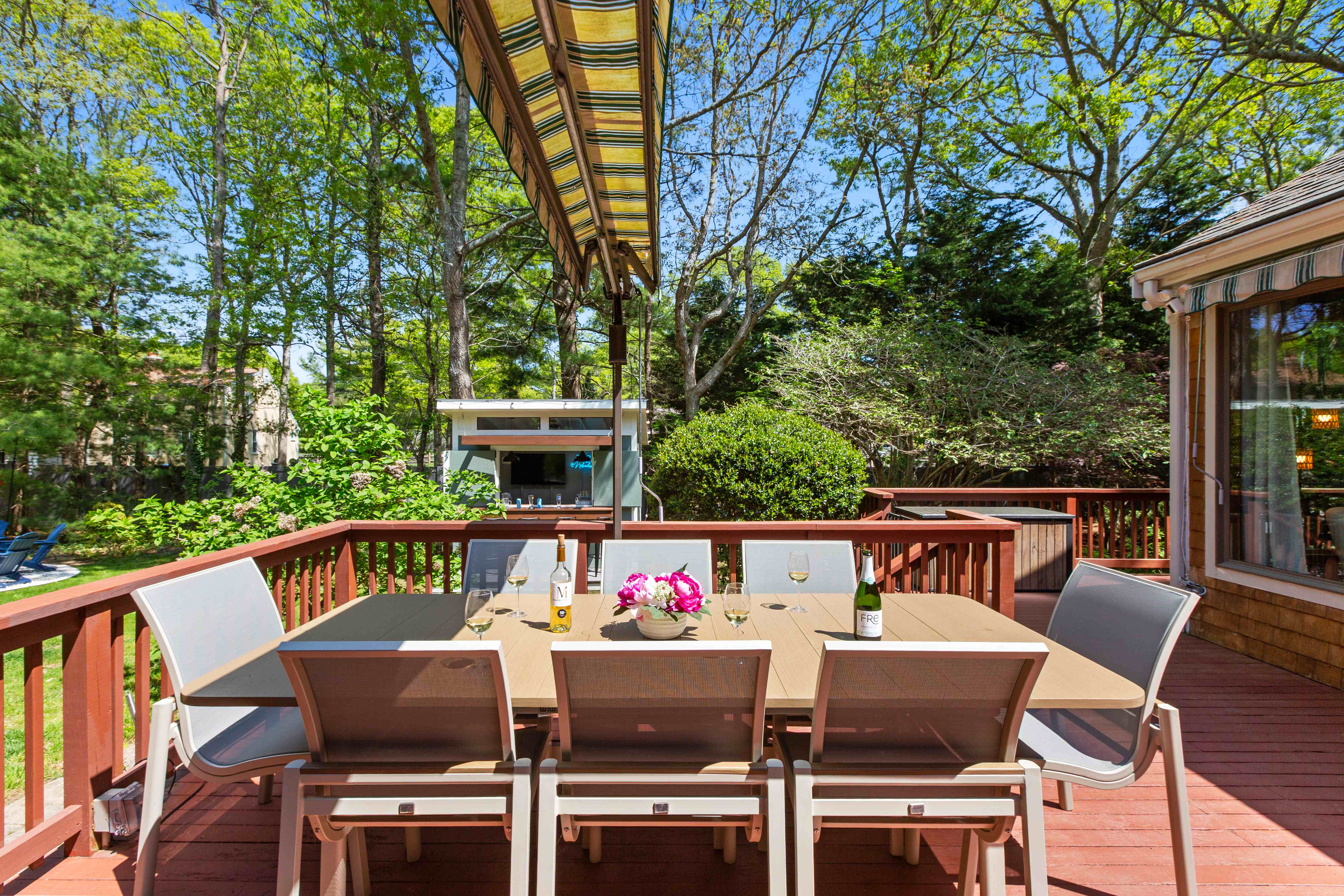 Deck dining table for eight set for wine beneath the awning at golden hour