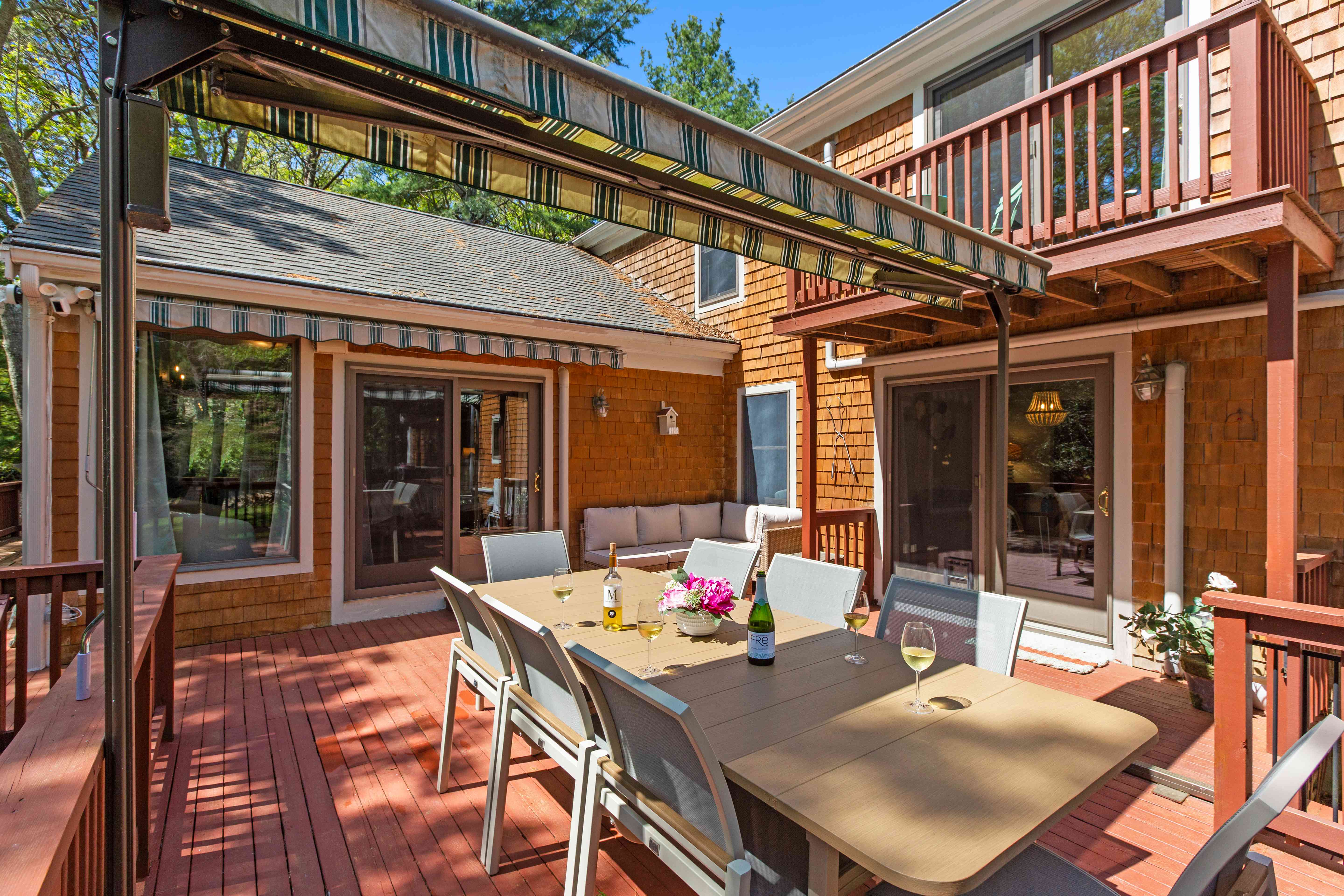 Deck dining table with the backyard bar shed visible among the trees