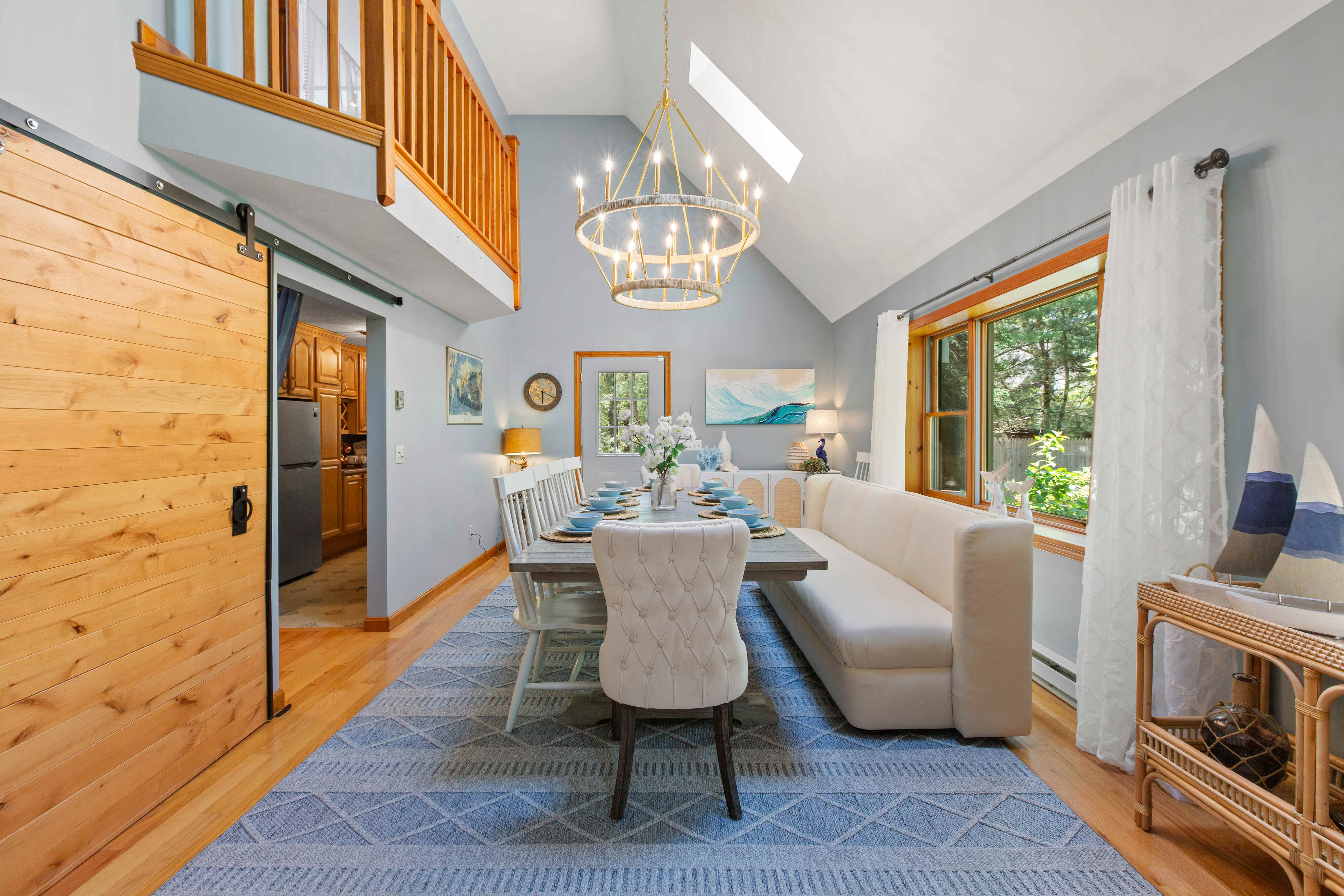 Dining table and banquette viewed from the barn door, with a pass-through to the kitchen and coastal wave art