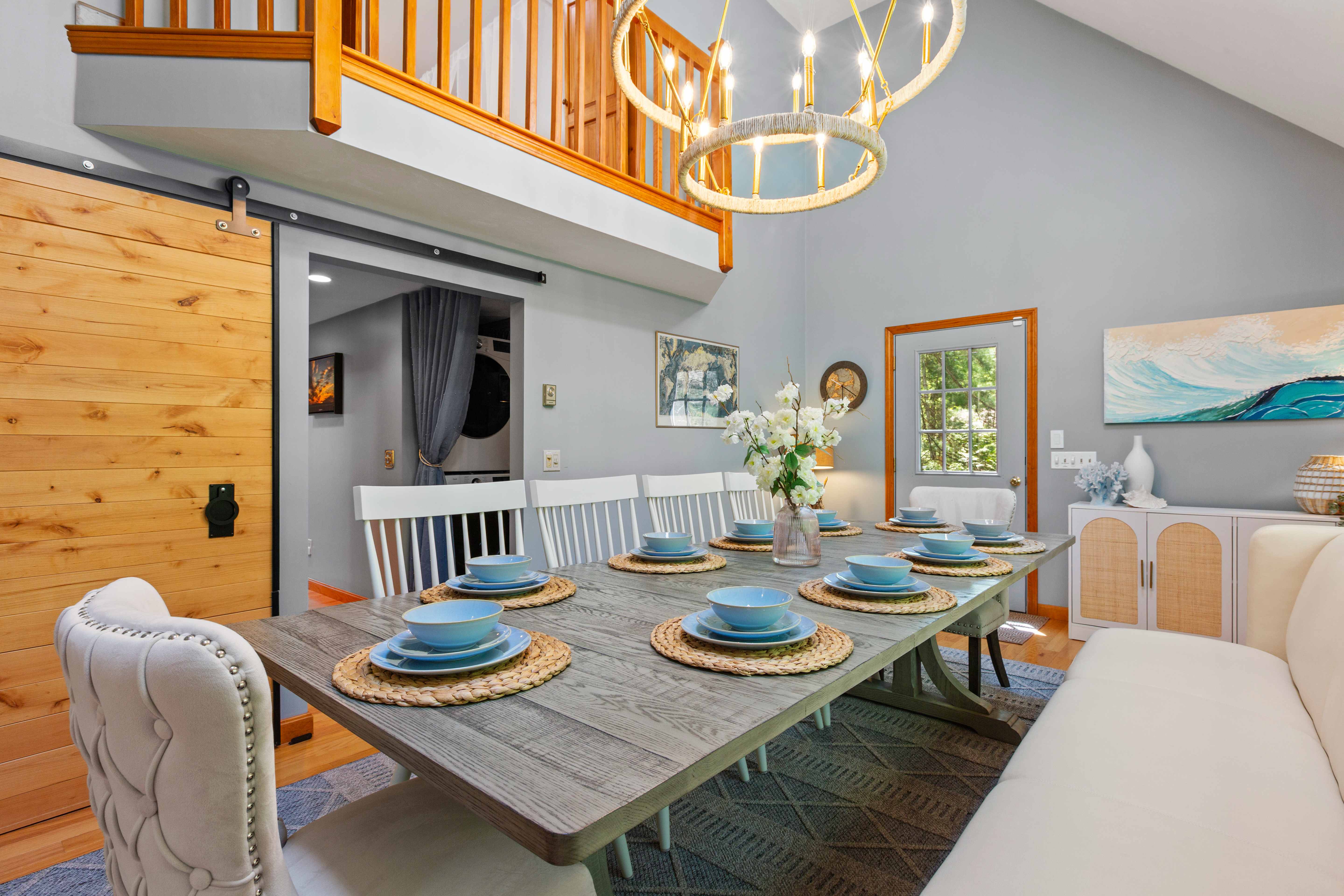Sliding barn door open to the laundry beside the set dining table, exterior door, and rattan cabinet