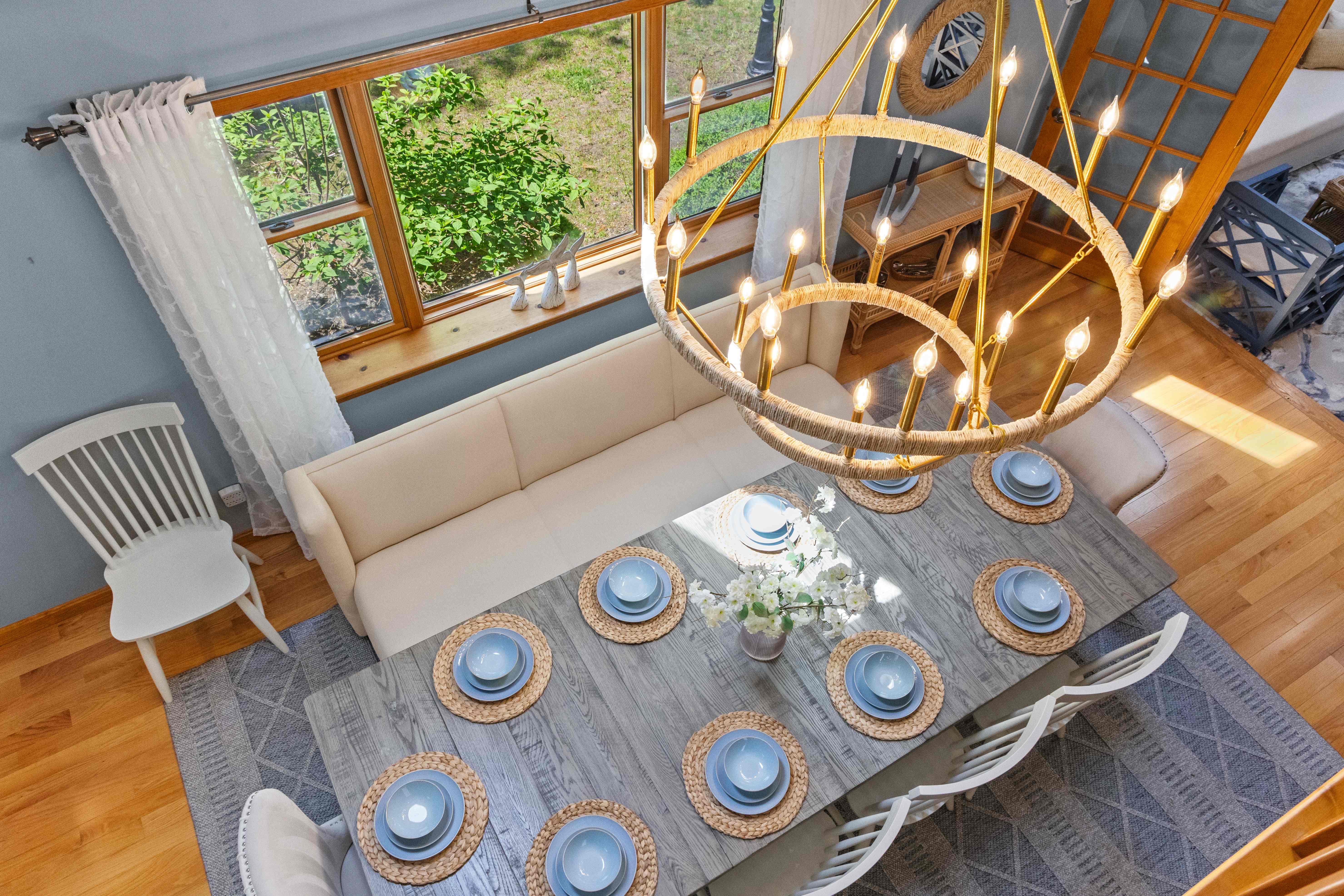 Overhead view from the loft looking down on the rope chandelier, dining table, and cream banquette
