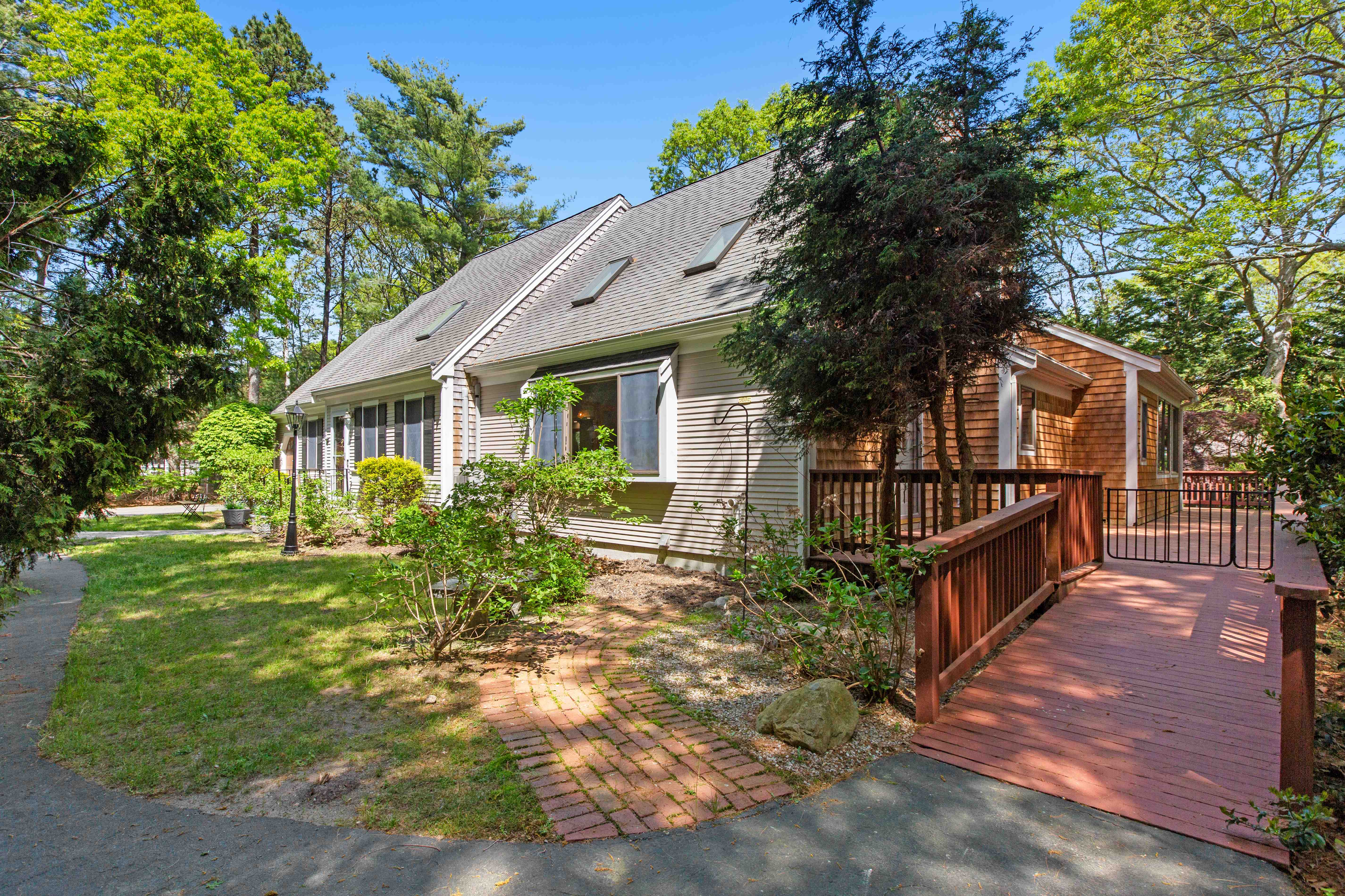 Side view down the length of the house with the cedar-shingled wing and wooden deck ramp