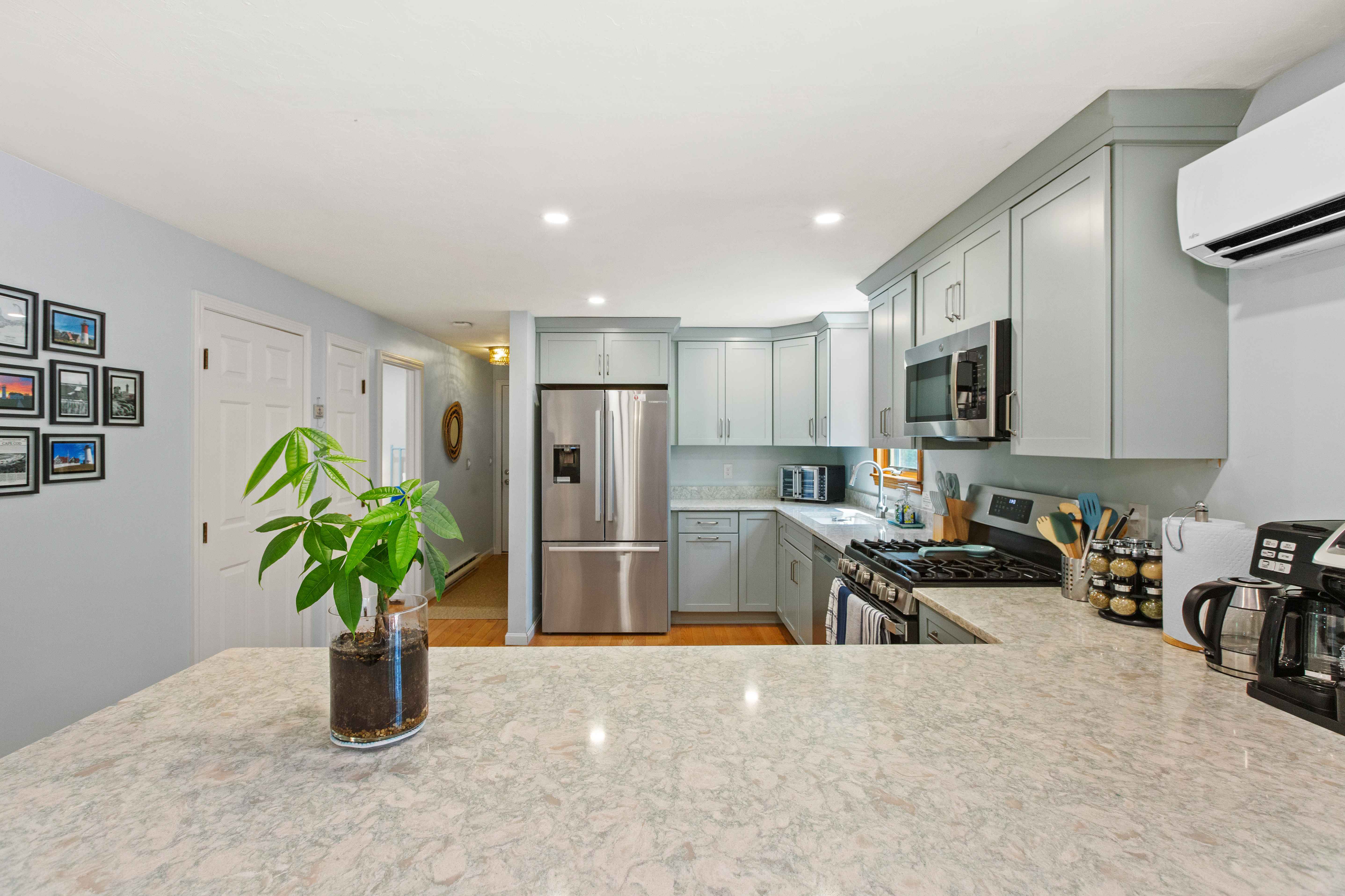 Kitchen peninsula with a gallery wall of framed lighthouse photographs beside the French-door refrigerator