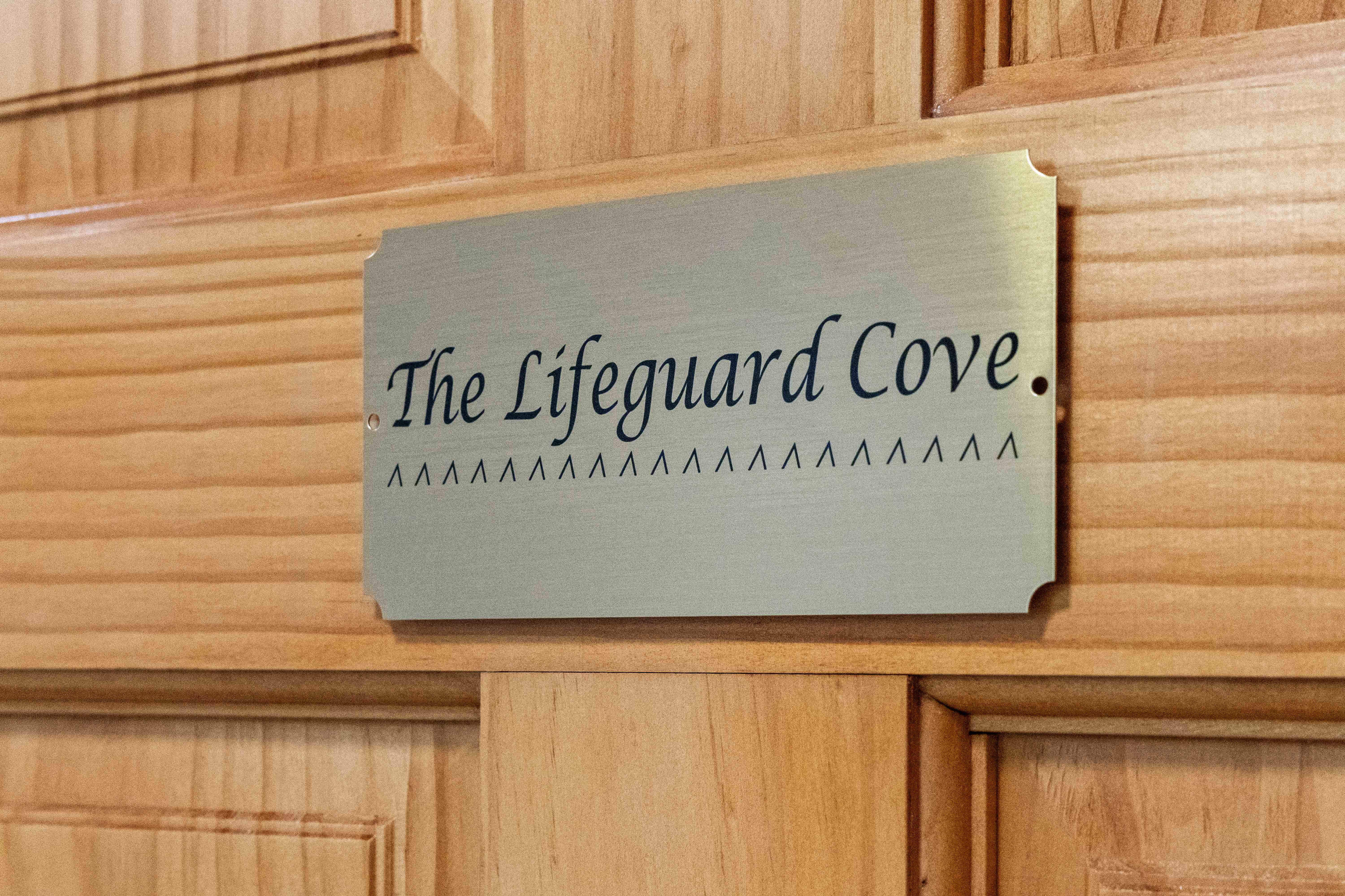 Close-up of the brushed-brass plaque engraved "The Lifeguard Cove"