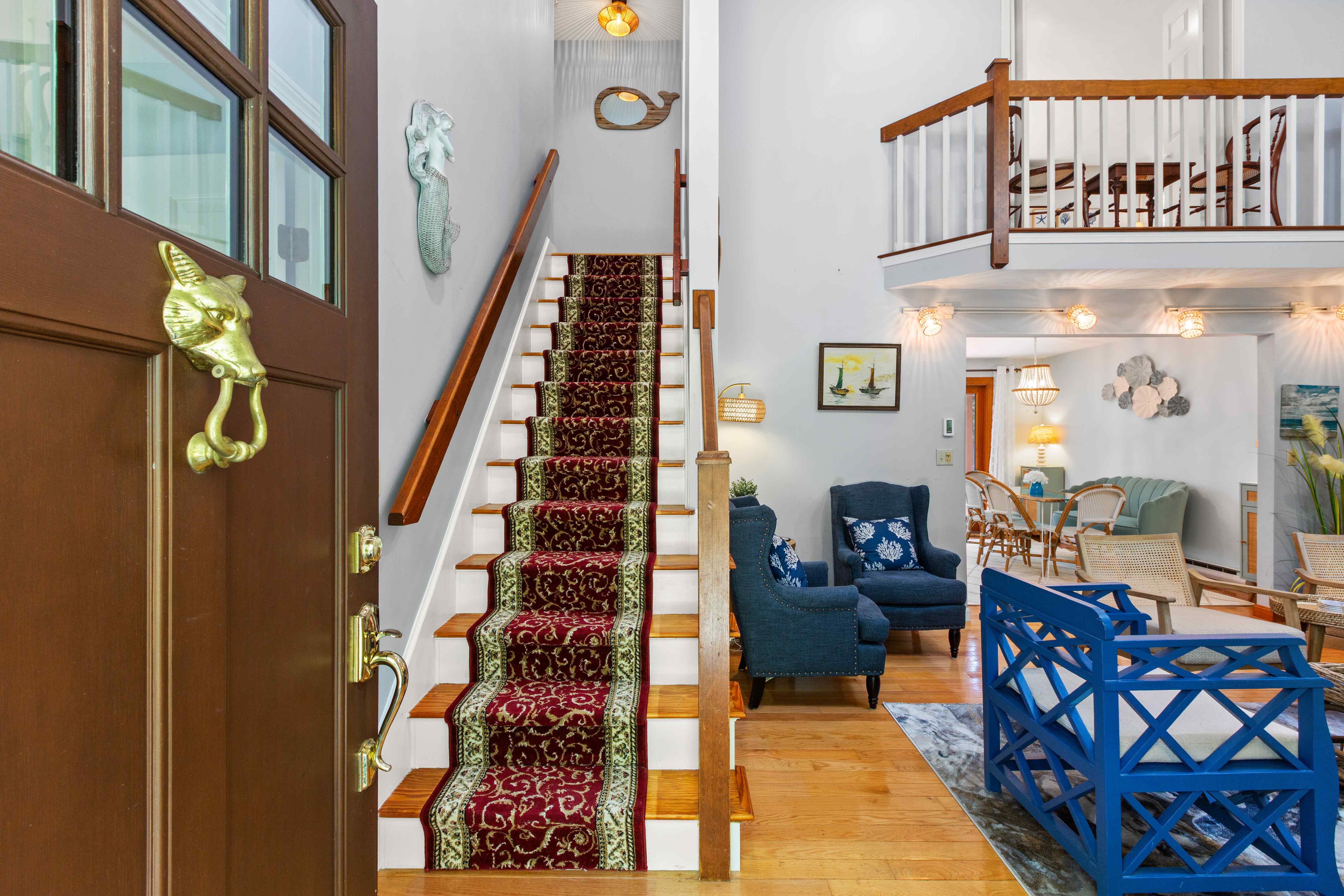 Entry foyer with a carpeted staircase, mermaid wall art, and views into the living room