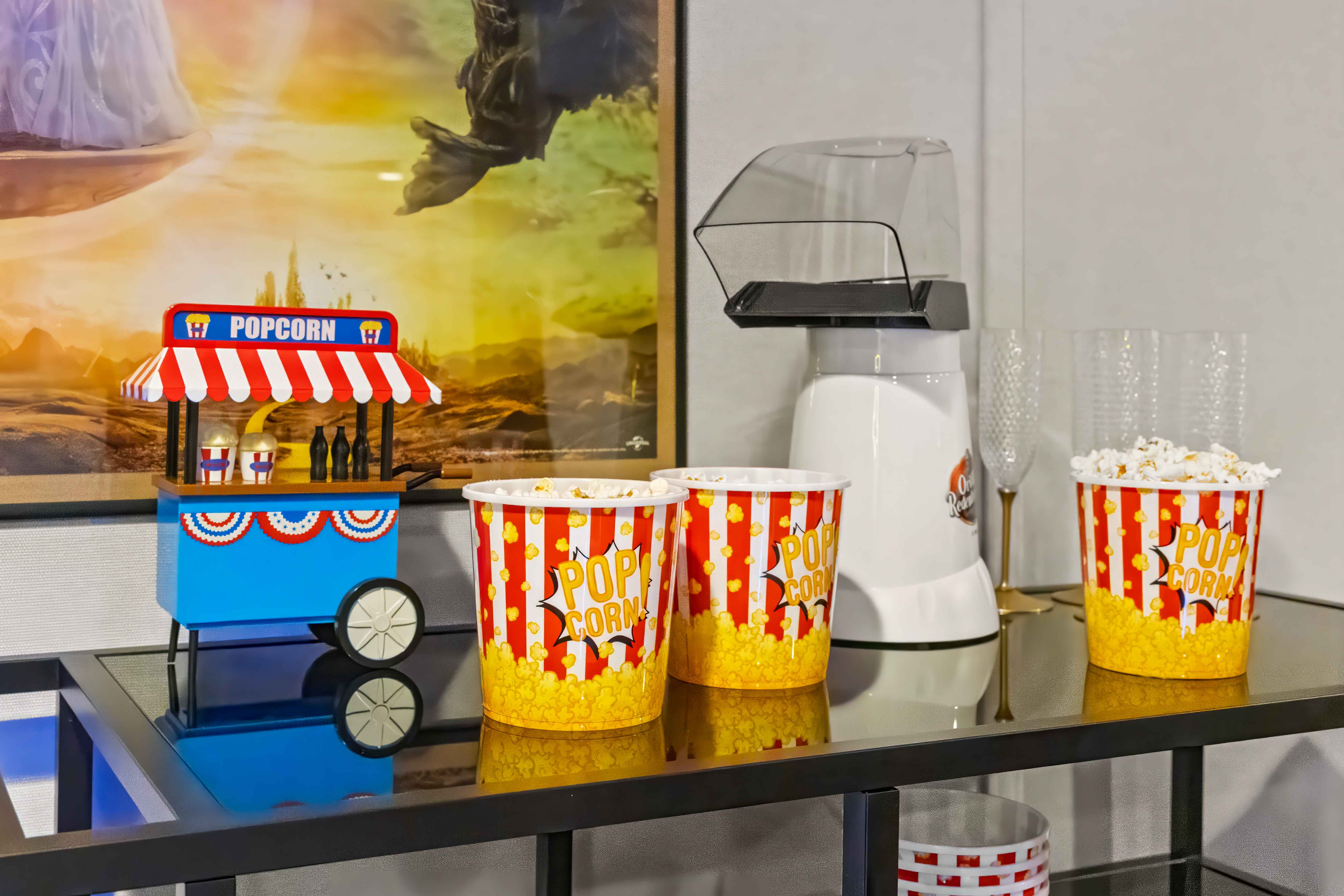 Popcorn station with a decorative popcorn cart, an air-popper machine, and red-and-white popcorn buckets